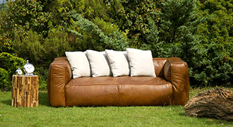 Canapé chiné dans un jardin entouré de quelques meubles.