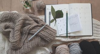Agenda, stylo, laine et pull posés sur une table
